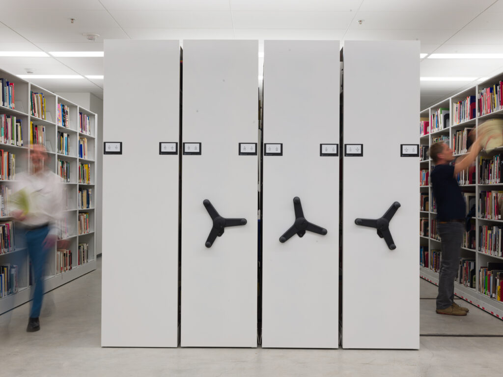 Two people take books down off a library shelf